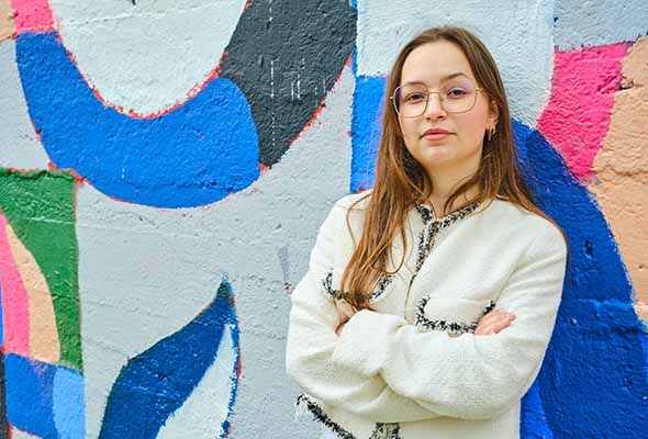 Jeune fille posant devant un mur coloré, l'air fière